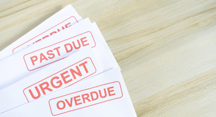 Debt letters that are collected on past overdue bills and final announcements on the table. Red writing to represent the struggle against economic unemployment.