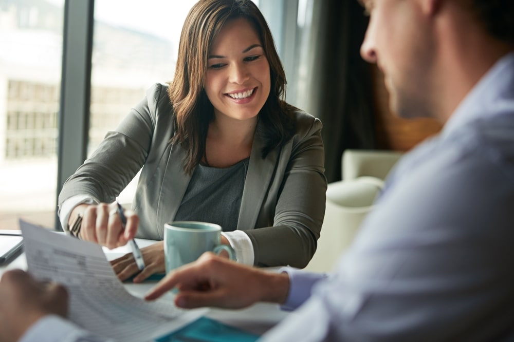 Smiling financial advisor reviewing tax debt program paperwork with client