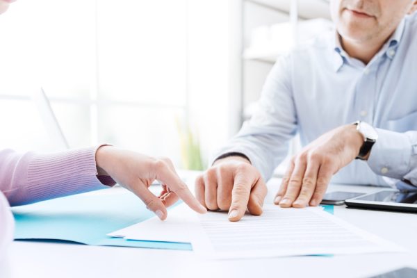 Tax advisor discusses forgiveness of tax debt with a client at a well-lit office desk.