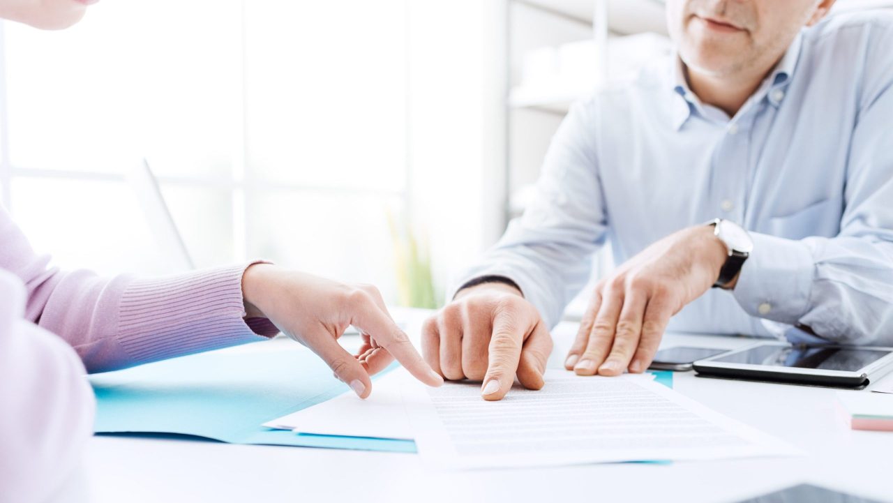 Tax advisor discusses forgiveness of tax debt with a client at a well-lit office desk.
