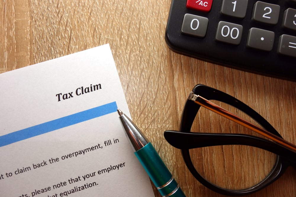 Tax claim paperwork with pen, calculator, and glasses on desk