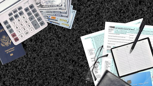 Tax documents, calculator, cash, passport and credit card on desk representing IRS debt and passport restrictions