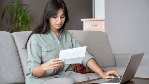 Woman reviewing IRS bad debt guidelines documentation while researching tax deduction requirements on laptop at home