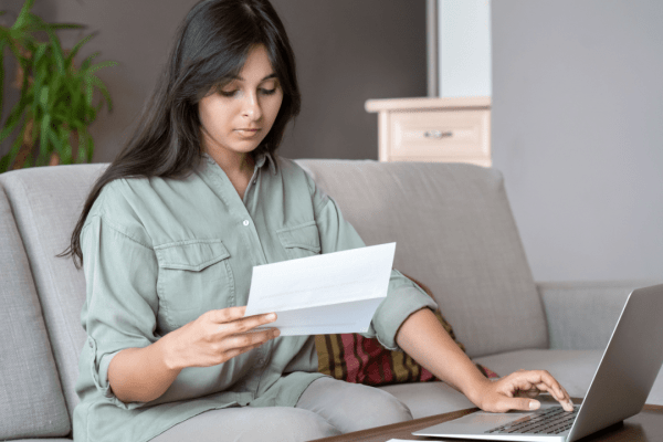 Woman reviewing IRS bad debt guidelines documentation while researching tax deduction requirements on laptop at home