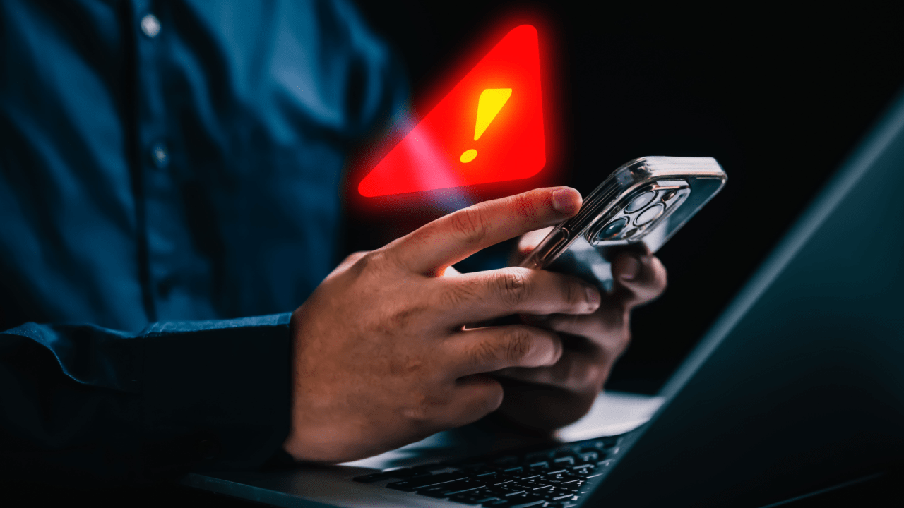 A person receiving a warning alert on a smartphone about an IRS tax debt voicemail scam notification