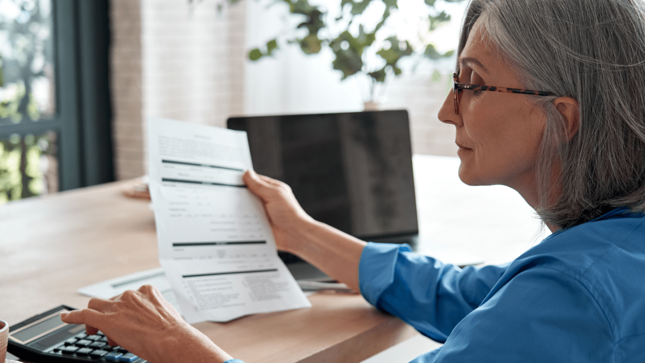 A senior woman reviewing tax documents at home while researching tax debt advisors for professional help