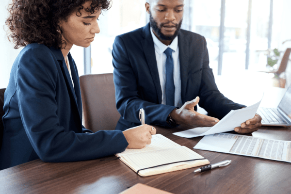 Tax professionals reviewing 0 tax owed debt relief program documentation while client takes notes during consultation meeting
