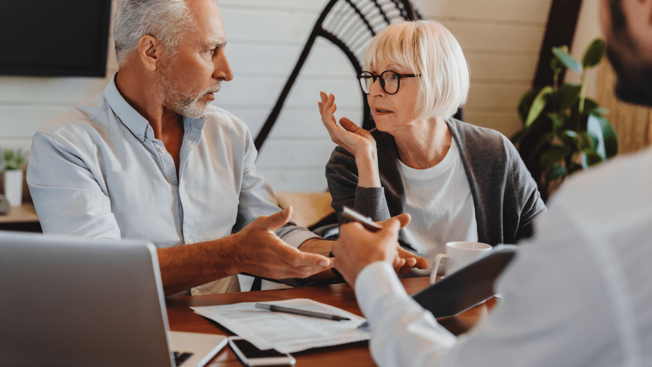 Senior couple dealing with tax debt concerns while discussing financial documents and relief options at home dining table