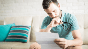 Stressed man holding glasses while reading IRS notice wondering do IRS debts expire and reviewing tax debt documentation