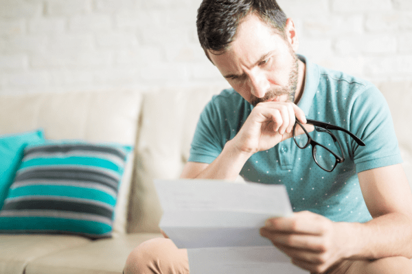 Stressed man holding glasses while reading IRS notice wondering do IRS debts expire and reviewing tax debt documentation