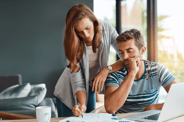 Worried couple researching does tax debt get passed down while reviewing estate planning and tax documents at home