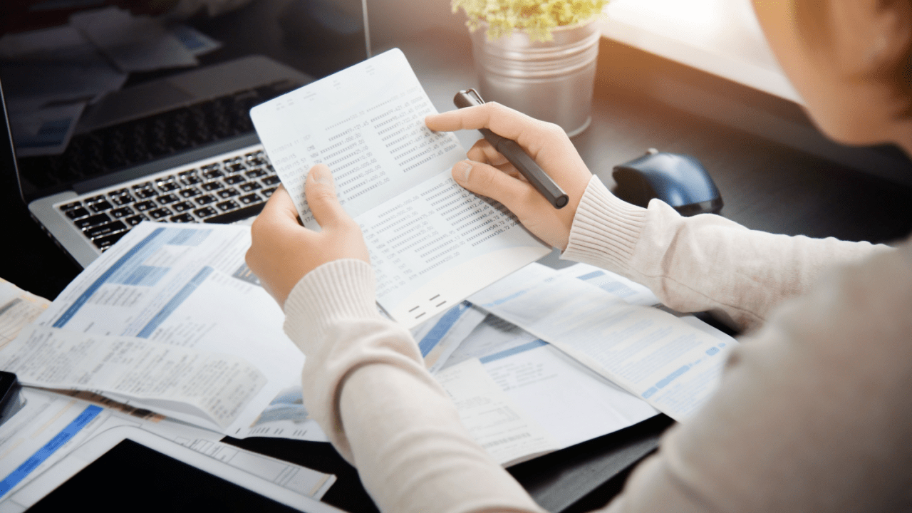 Person researching IRS debt consolidation companies while reviewing tax debt relief documents and financial reports at desk