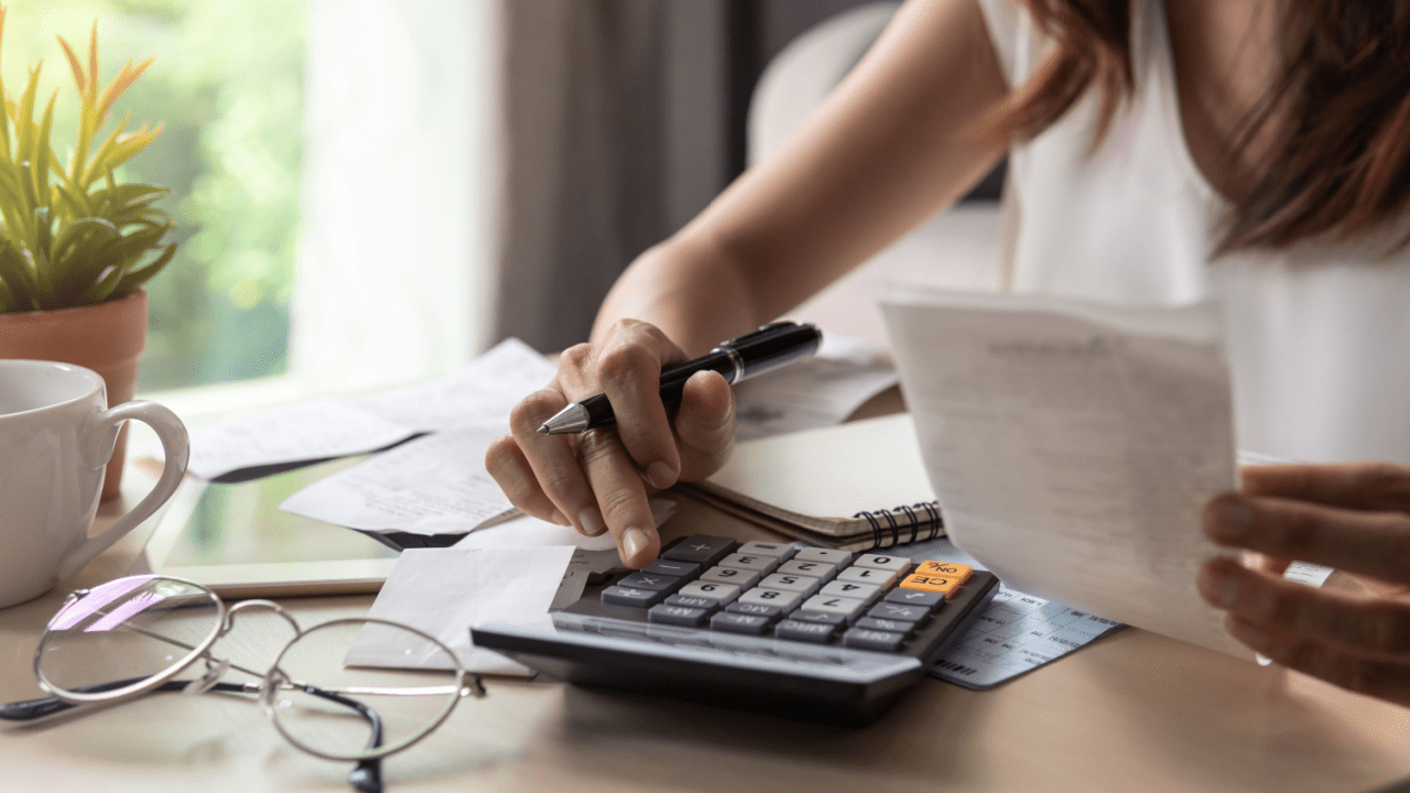 Woman calculating tax obligations while reviewing IRS debt lien list documents and financial paperwork at home office desk