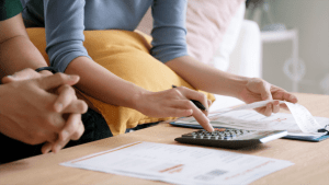 Couple calculating tax debt 2024 obligations using calculator and financial documents at home