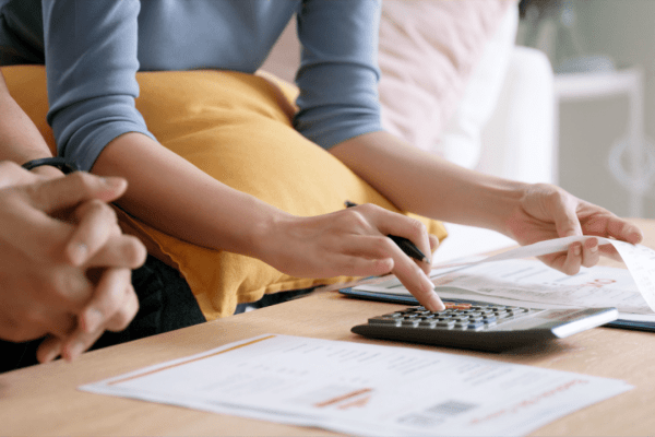 Couple calculating tax debt 2024 obligations using calculator and financial documents at home