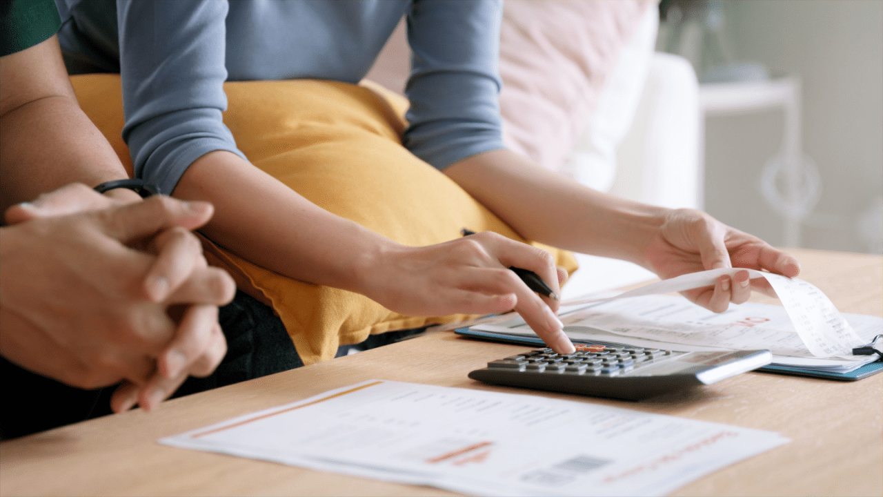 Couple calculating tax debt 2024 obligations using calculator and financial documents at home