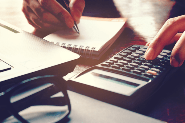 Person calculating and planning strategy for paying off a tax debt using calculator and financial documents