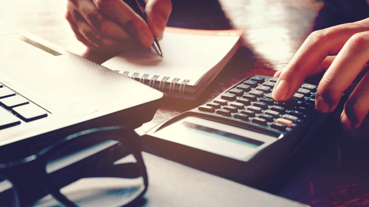 Person calculating and planning strategy for paying off a tax debt using calculator and financial documents