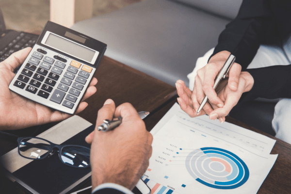 Business professionals calculating tax debt after 10 years statute limitations using calculator while reviewing financial charts and data