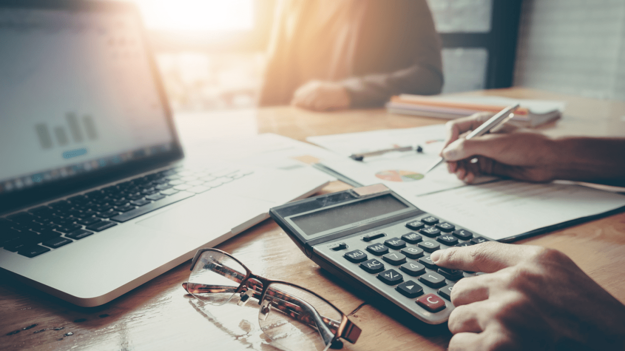 Person calculating tax debt Chapter 13 payment plan amounts using calculator while reviewing bankruptcy documents and financial charts
