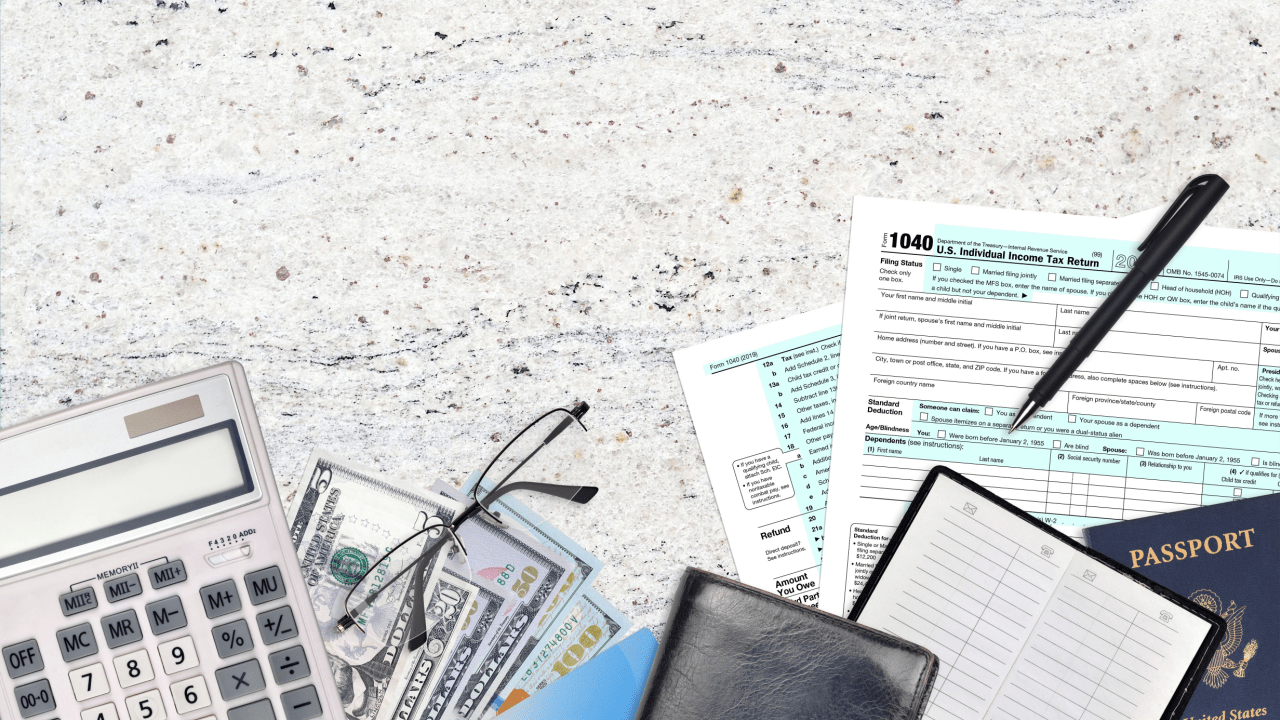 Tax debt passport restrictions concept showing IRS forms, calculator, cash, and US passport on desk