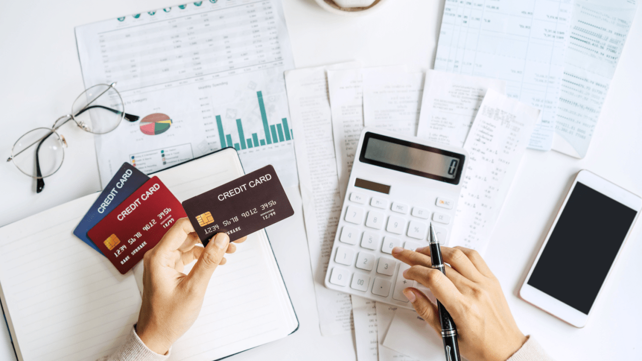Person calculating tax debt write off options using credit cards, calculator and financial documents on desk