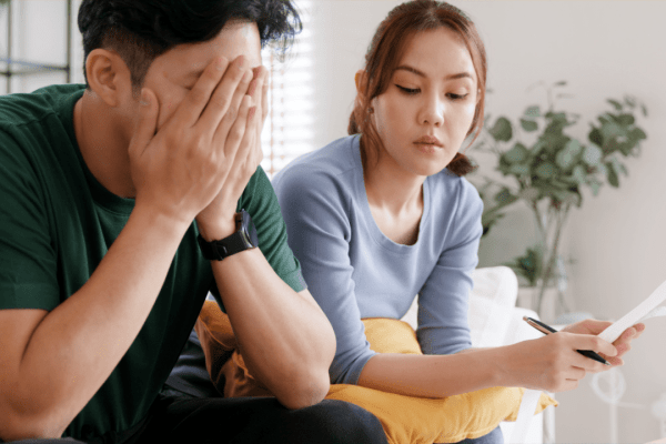 Stressed couple wondering is the IRS really forgiving tax debt while reviewing financial documents