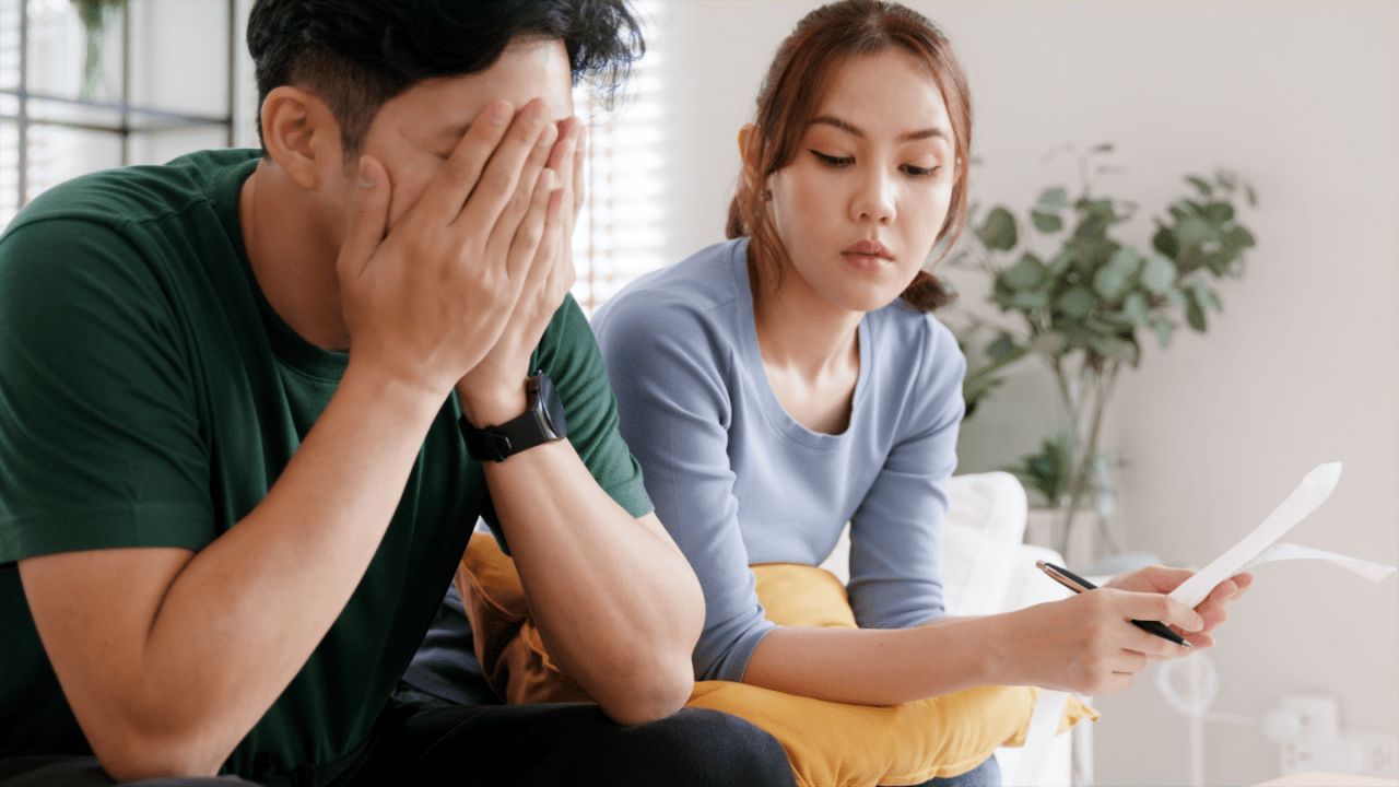 Stressed couple wondering is the IRS really forgiving tax debt while reviewing financial documents