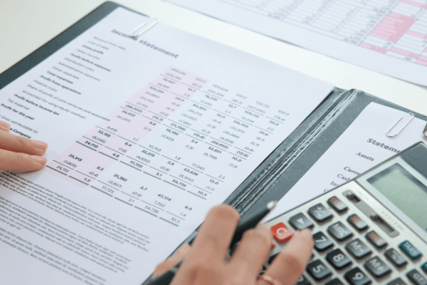 Person calculating how serious is tax debt using calculator with financial statements and tax documents