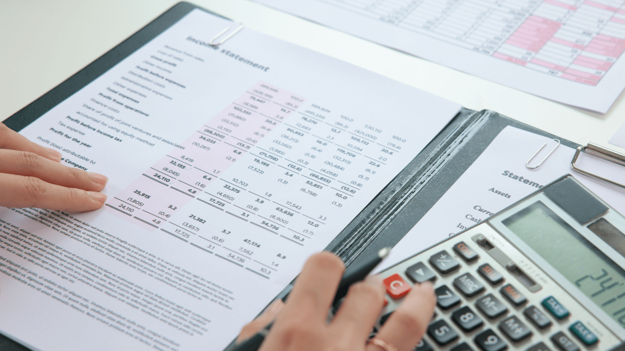Person calculating how serious is tax debt using calculator with financial statements and tax documents