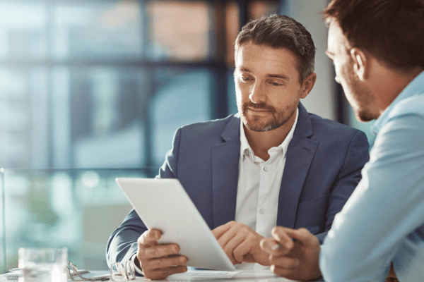 Tax professional consulting with client about how to resolve IRS debt while reviewing tax relief documents in modern office setting