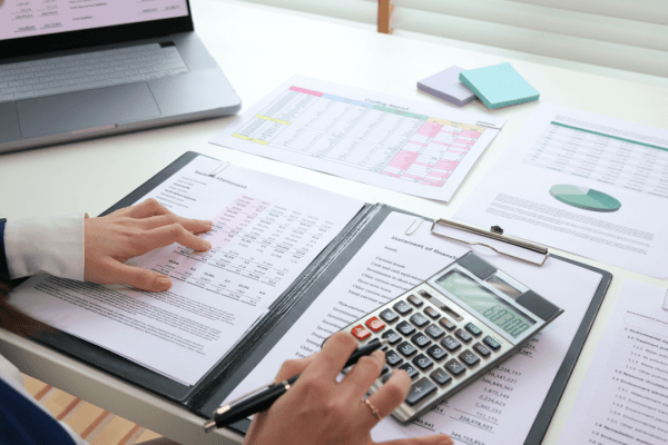 Tax professional reviewing financial documents to understand tax debt definition using calculator and laptop