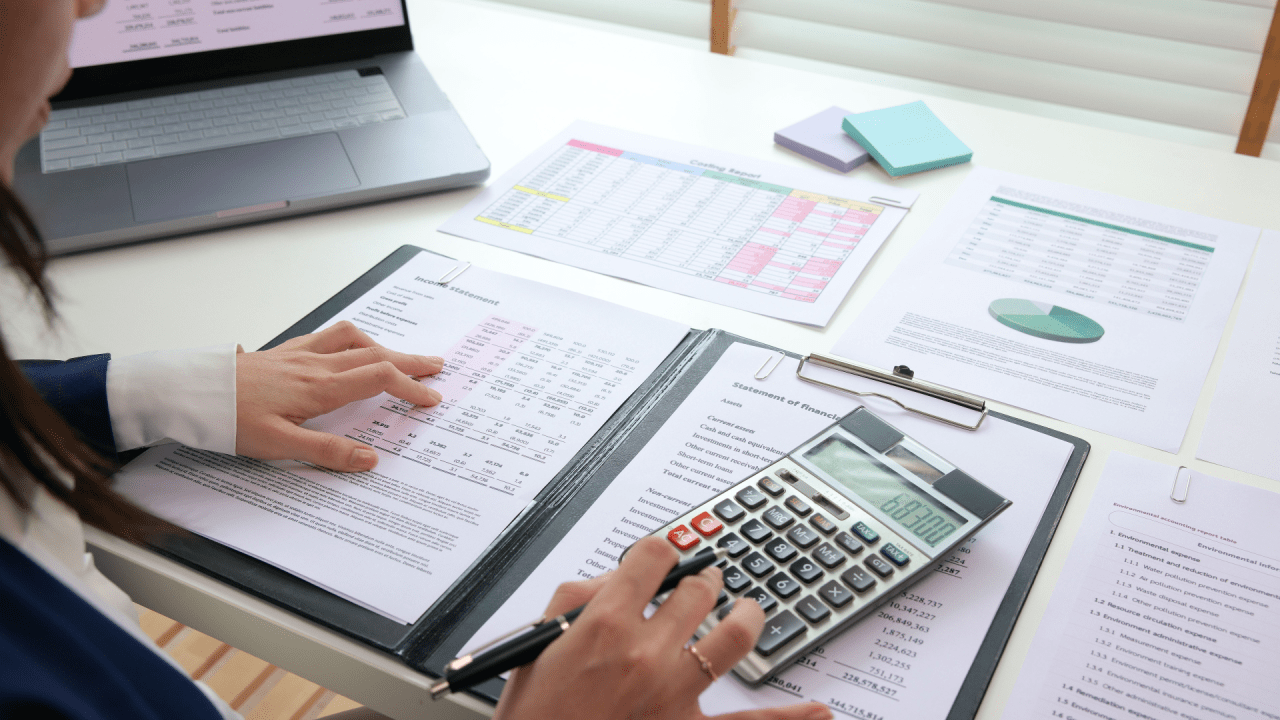 Tax professional reviewing financial documents to understand tax debt definition using calculator and laptop