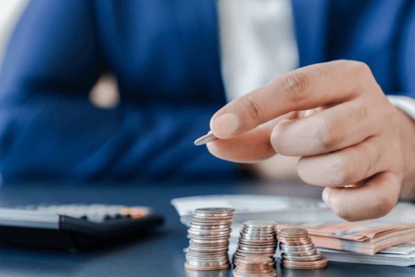 Business professional arranging coins to demonstrate tax debt installment plan payment structure with calculator and cash