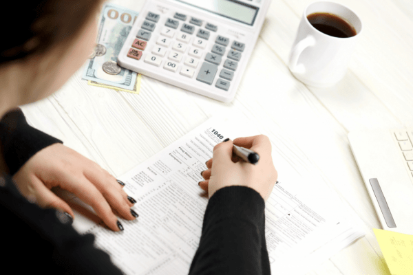 Woman completing Form 1040 while researching whether IRS debt is considered federal debt with calculator and laptop