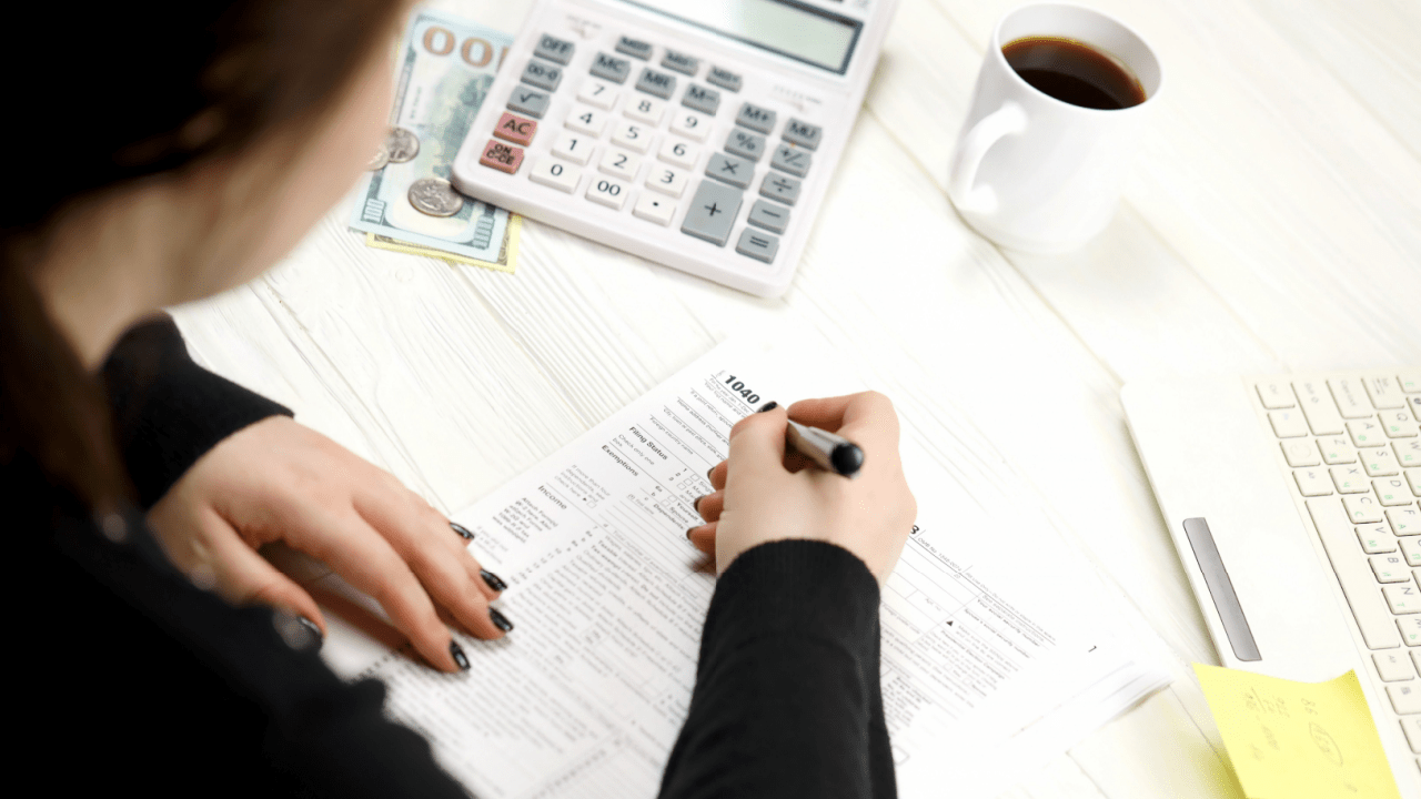 Woman completing Form 1040 while researching whether IRS debt is considered federal debt with calculator and laptop
