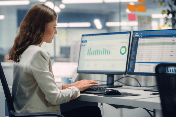 Professional woman researching what to do if you owe IRS and can't pay using financial software on dual monitors