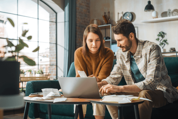 Couple researching who is eligible for the Fresh Start Program on laptop with tax documents