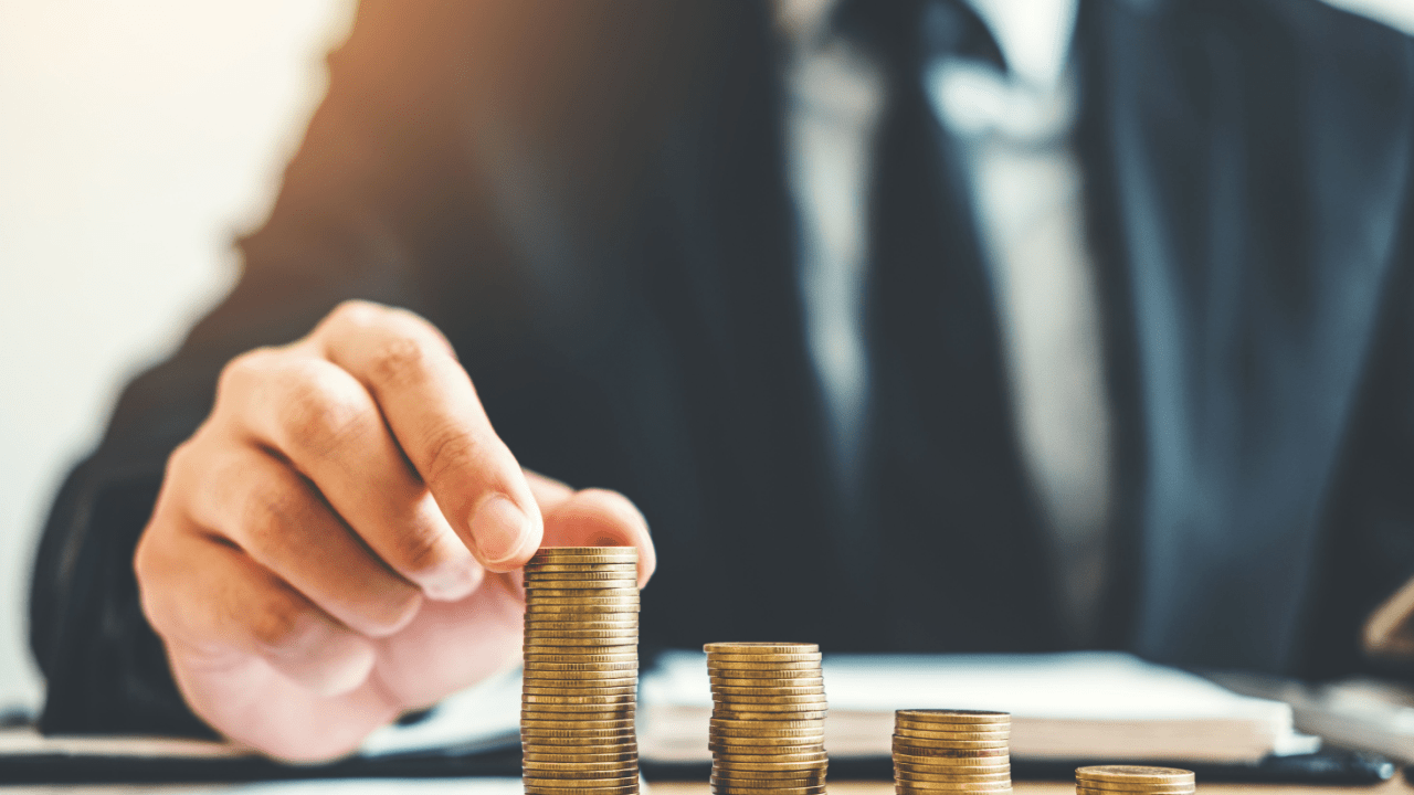 Professional in business suit stacking coins showing do tax advocates cost money investment concept