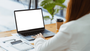 Person researching how much does it cost to hire a tax advisor on laptop at modern workspace with coffee and documents