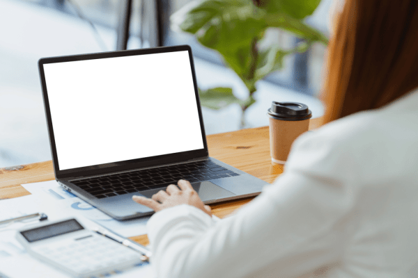 Person researching how much does it cost to hire a tax advisor on laptop at modern workspace with coffee and documents