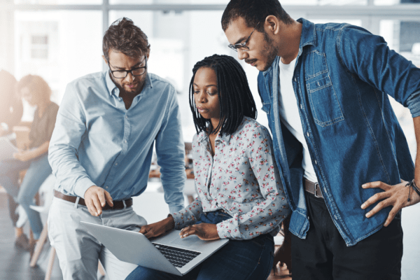 Three professionals collaborating on laptop discussing how to find a good tax lawyer for their business