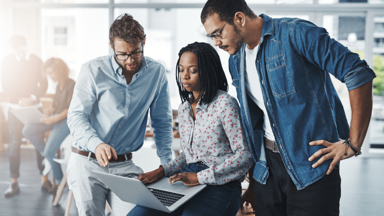 Three professionals collaborating on laptop discussing how to find a good tax lawyer for their business