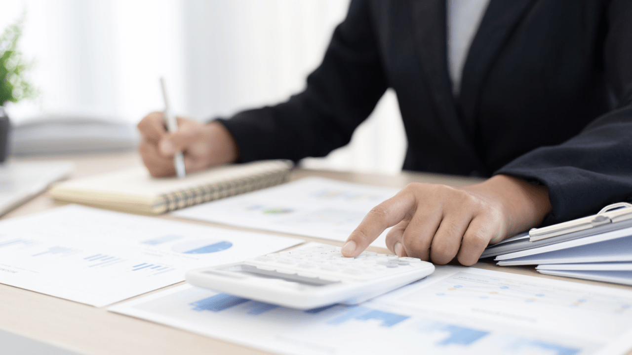 Professional calculating how much will the IRS usually settle for using calculator and financial documents