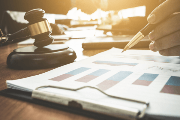 Professional reviewing financial documents and charts for settling and negotiating tax debt with gavel on desk