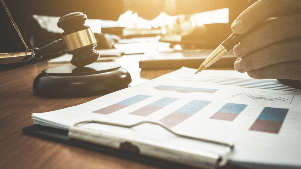 Professional reviewing financial documents and charts for settling and negotiating tax debt with gavel on desk