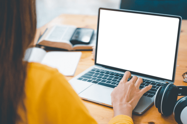 Person in yellow shirt researching what is a tax lawyer called on laptop at wooden desk with books and documents
