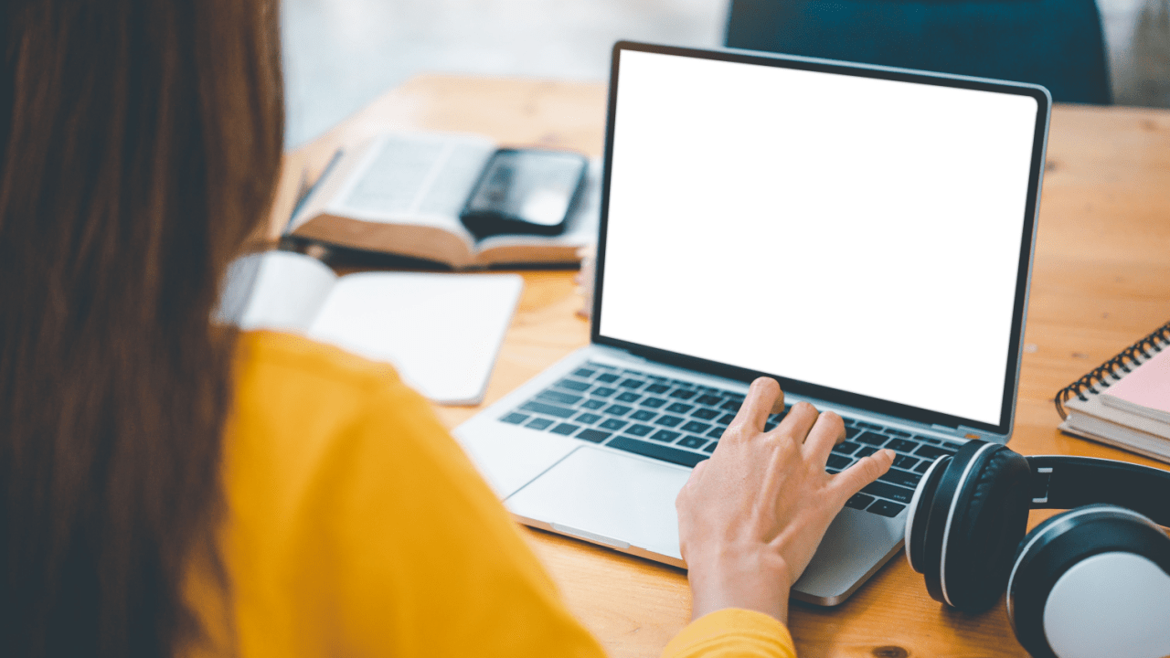 Person in yellow shirt researching what is a tax lawyer called on laptop at wooden desk with books and documents