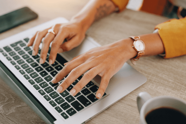 Professional hands typing on laptop researching benefits of hiring a tax attorney for IRS problems while working at home office with coffee