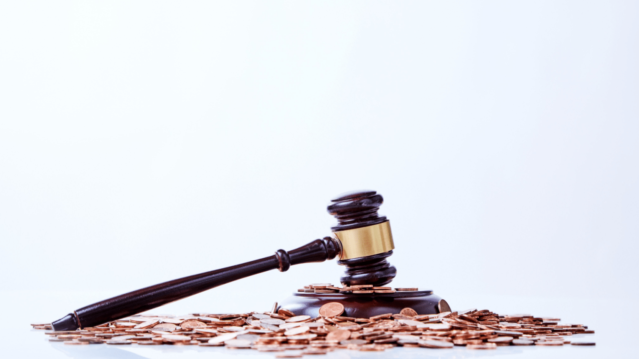 Wooden gavel on pile of coins representing can you deduct legal fees for tax